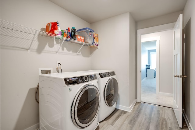 washroom with light hardwood / wood-style floors and washing machine and clothes dryer