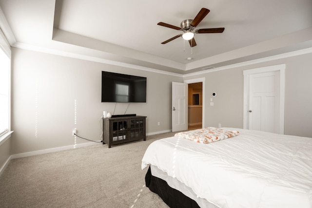 carpeted bedroom with a raised ceiling, ceiling fan, and crown molding