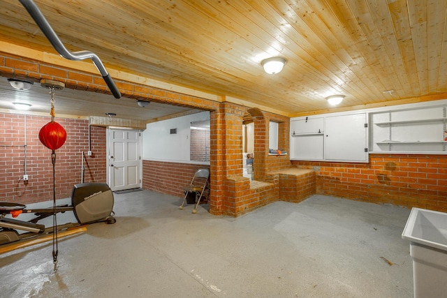 basement featuring wood ceiling and brick wall