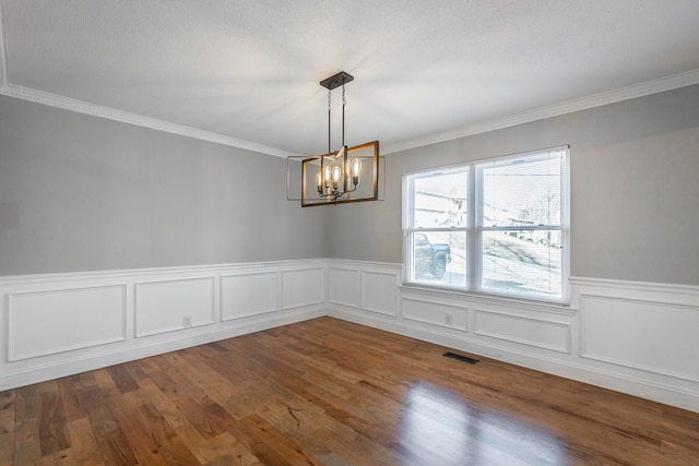 spare room with dark hardwood / wood-style flooring, crown molding, and a chandelier