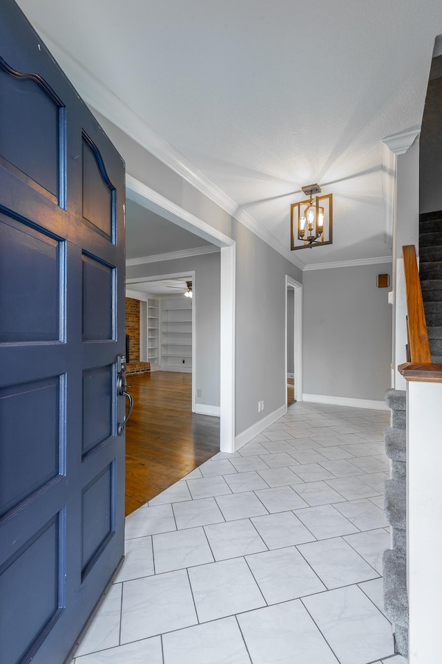 foyer featuring ceiling fan with notable chandelier, ornamental molding, and light tile patterned flooring