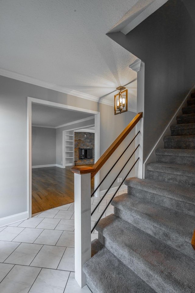 stairway featuring built in shelves, tile patterned floors, crown molding, a chandelier, and a textured ceiling