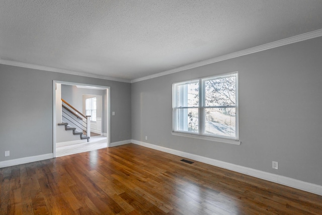 empty room with hardwood / wood-style floors, ornamental molding, and a textured ceiling