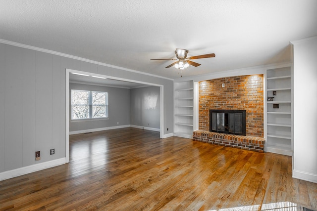 unfurnished living room with crown molding, built in features, wood-type flooring, and a textured ceiling