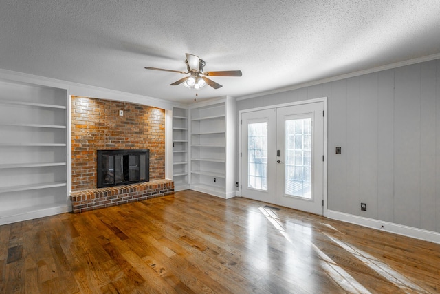 unfurnished living room with ceiling fan, built in features, a textured ceiling, and french doors