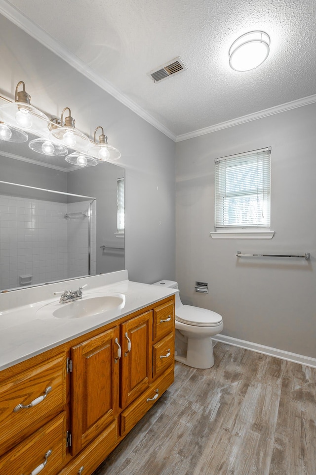 bathroom with ornamental molding, a textured ceiling, toilet, vanity, and hardwood / wood-style flooring