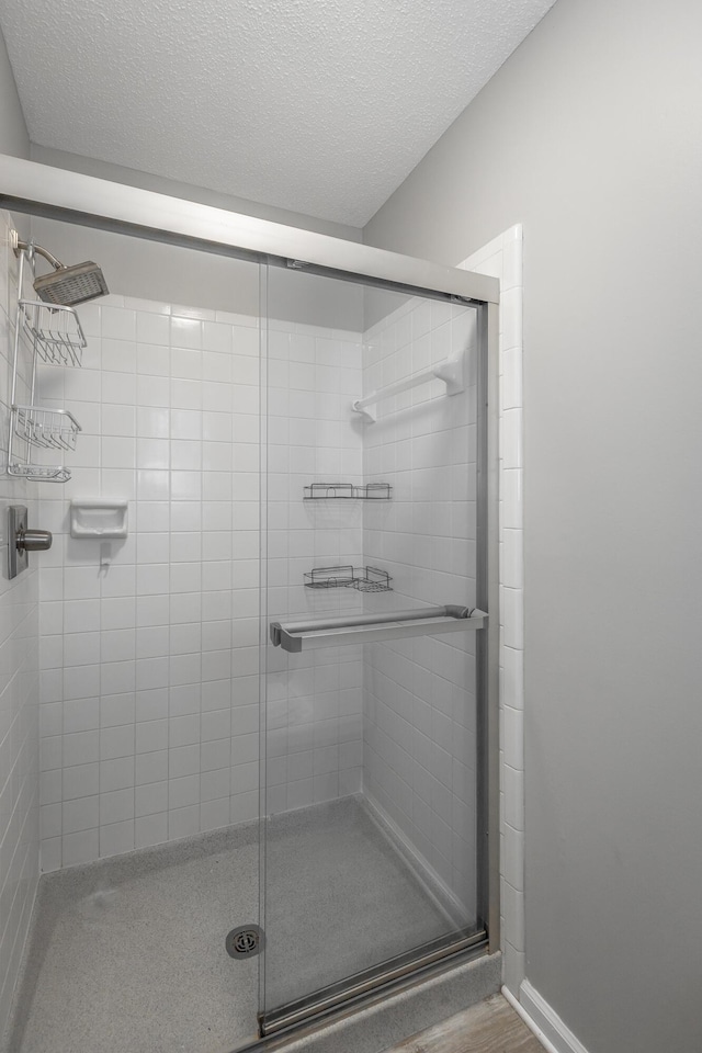 bathroom featuring a textured ceiling and a shower with door