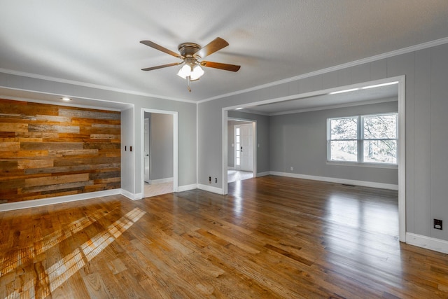 unfurnished room with hardwood / wood-style flooring, ceiling fan, ornamental molding, and wood walls