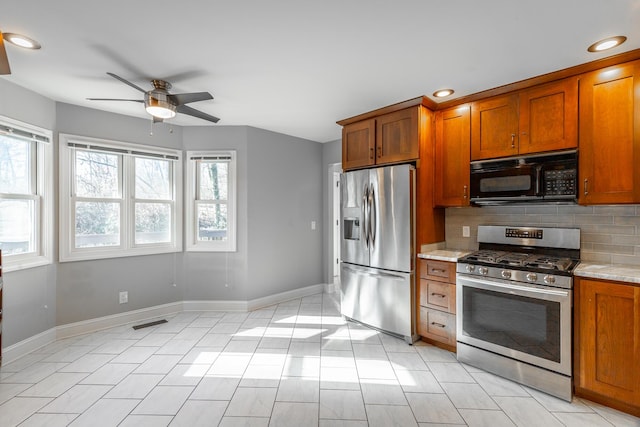 kitchen with ceiling fan, light stone countertops, stainless steel appliances, and tasteful backsplash