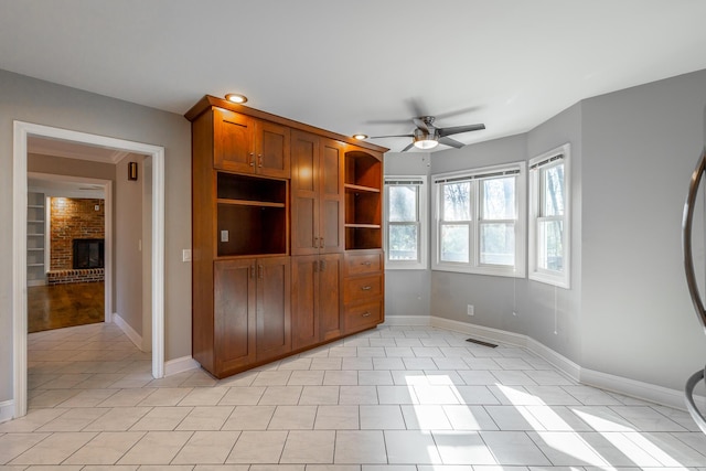 interior space with ceiling fan, light tile patterned floors, and a fireplace