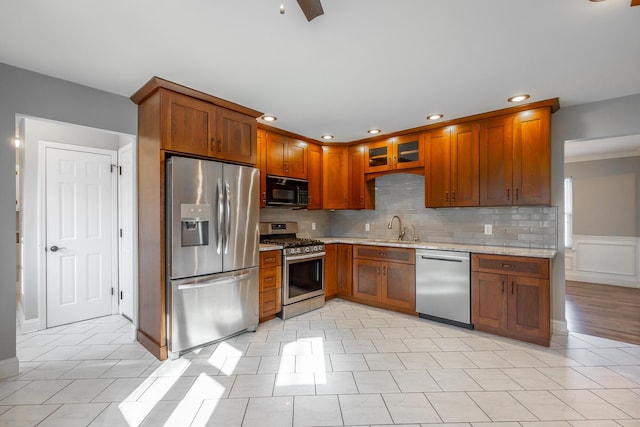 kitchen featuring light stone countertops, backsplash, stainless steel appliances, sink, and light tile patterned flooring