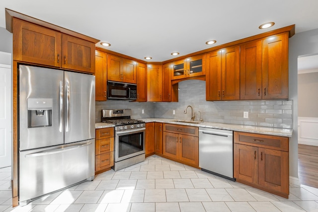 kitchen featuring light stone countertops, sink, backsplash, light tile patterned floors, and appliances with stainless steel finishes