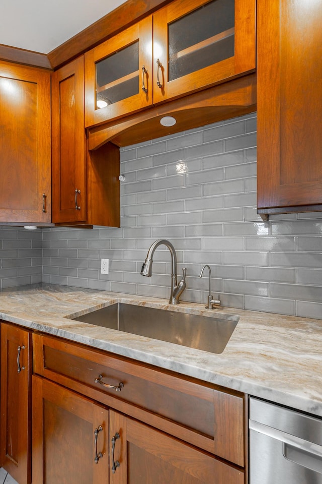 kitchen with dishwasher, tasteful backsplash, light stone counters, and sink