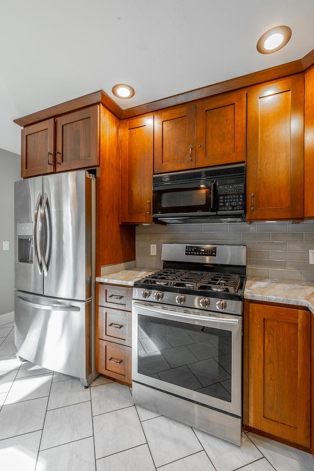 kitchen with backsplash, light stone counters, light tile patterned floors, and stainless steel appliances