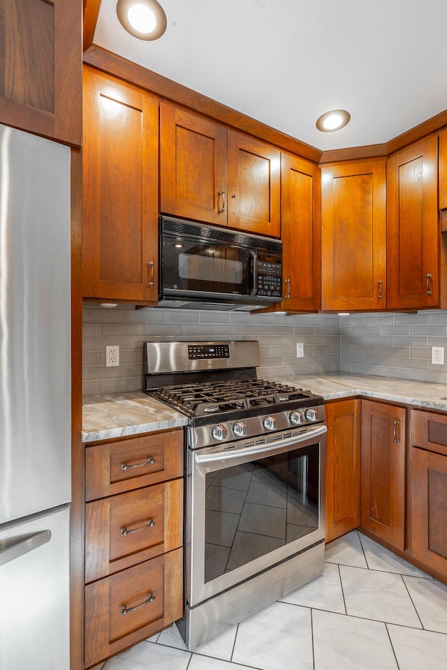 kitchen featuring light stone countertops, appliances with stainless steel finishes, backsplash, and light tile patterned floors