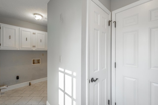 clothes washing area with cabinets, hookup for a washing machine, a textured ceiling, and light tile patterned floors