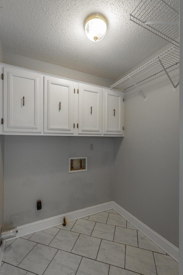 washroom featuring hookup for a washing machine, cabinets, and a textured ceiling