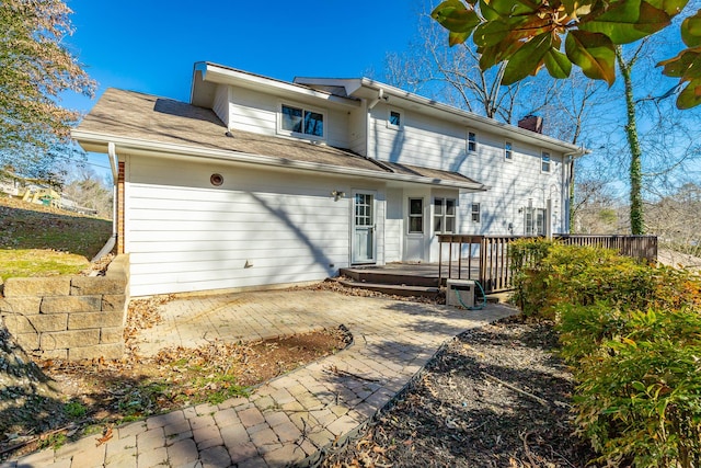 back of house with a wooden deck and a patio