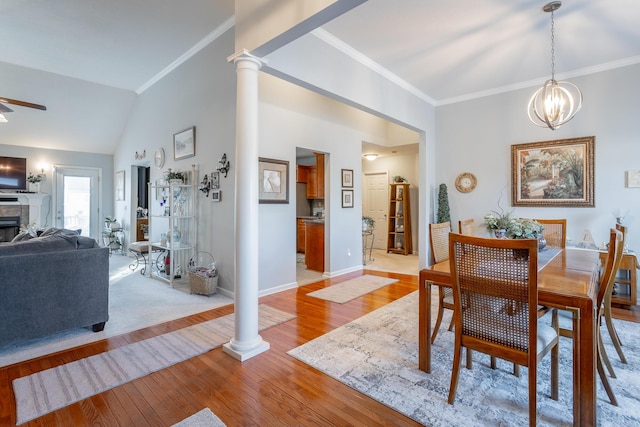 dining area with decorative columns, vaulted ceiling, light hardwood / wood-style floors, ceiling fan with notable chandelier, and crown molding