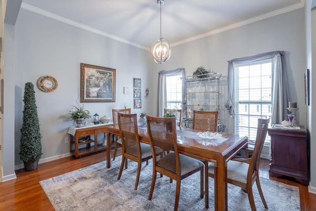 dining space with wood-type flooring, crown molding, and a notable chandelier