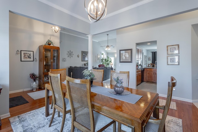 dining space with ornamental molding, light hardwood / wood-style flooring, decorative columns, and ceiling fan with notable chandelier