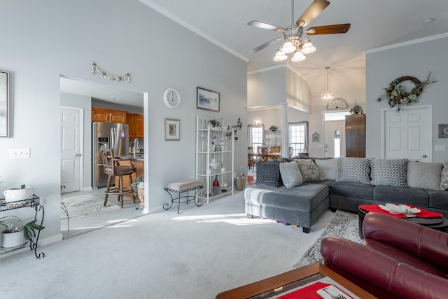 carpeted living room with ornamental molding, high vaulted ceiling, and ceiling fan with notable chandelier