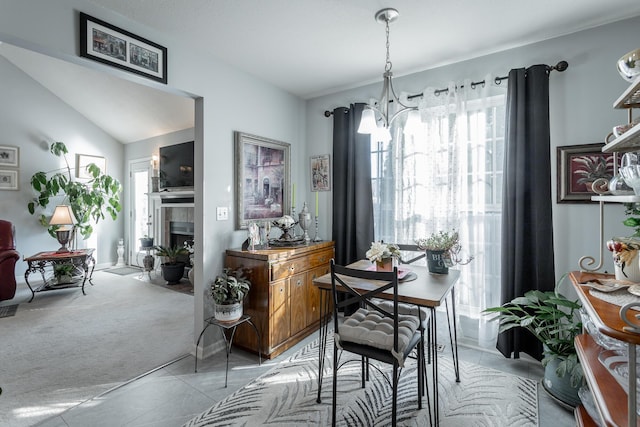 dining area featuring a notable chandelier, light colored carpet, a tile fireplace, and plenty of natural light