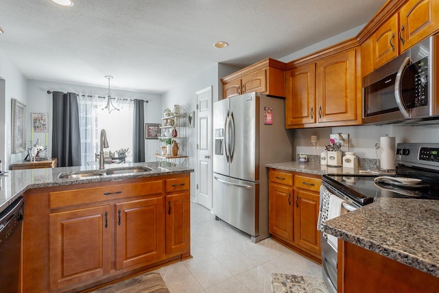 kitchen featuring sink, stainless steel appliances, dark stone counters, and an inviting chandelier