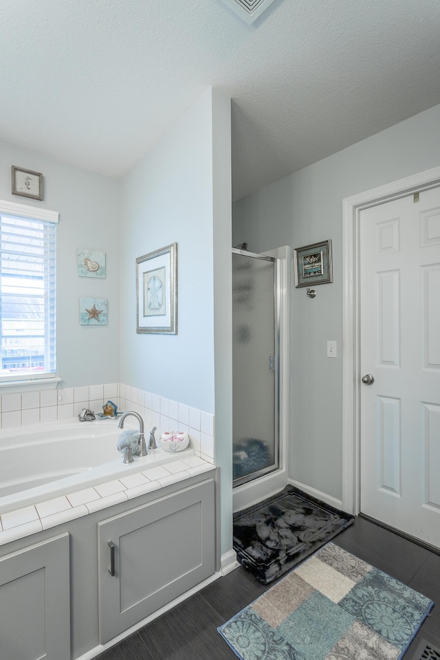 bathroom with independent shower and bath, hardwood / wood-style floors, and a textured ceiling