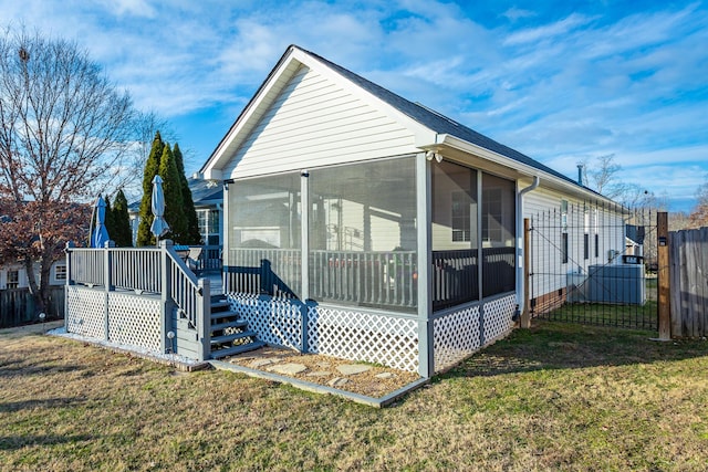 view of side of home featuring a lawn, a deck, and a sunroom