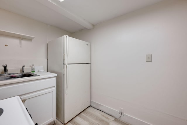 kitchen with white refrigerator, light hardwood / wood-style floors, white cabinets, and sink