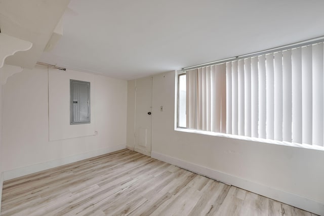 spare room with electric panel and light wood-type flooring