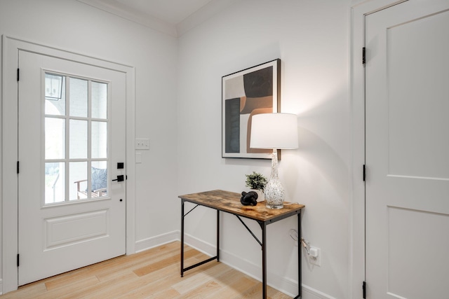 doorway with plenty of natural light, light hardwood / wood-style floors, and ornamental molding