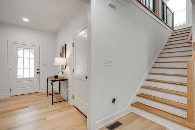 foyer entrance with light hardwood / wood-style floors and ornamental molding