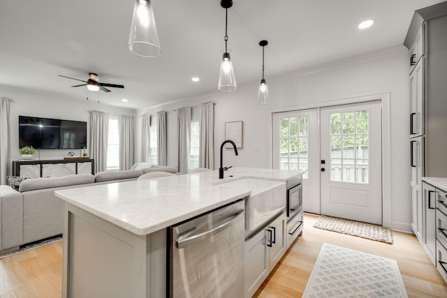 kitchen with pendant lighting, a center island with sink, sink, ceiling fan, and stainless steel appliances