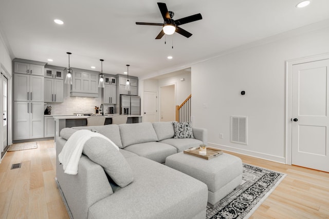 living room featuring ceiling fan, crown molding, and light hardwood / wood-style floors