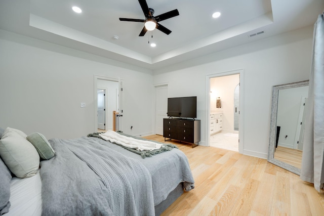 bedroom featuring ensuite bathroom, a raised ceiling, and ceiling fan