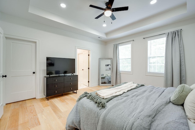 bedroom featuring a tray ceiling, ceiling fan, and light hardwood / wood-style floors