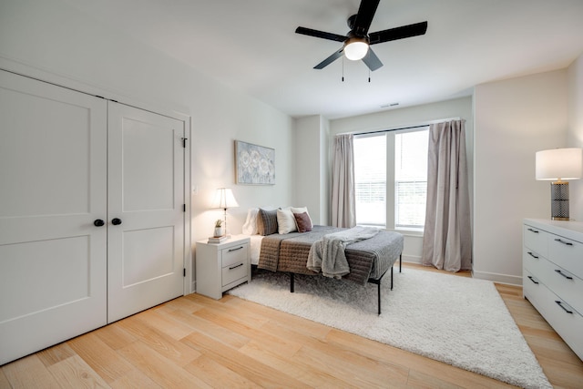 bedroom with ceiling fan, light hardwood / wood-style floors, and a closet