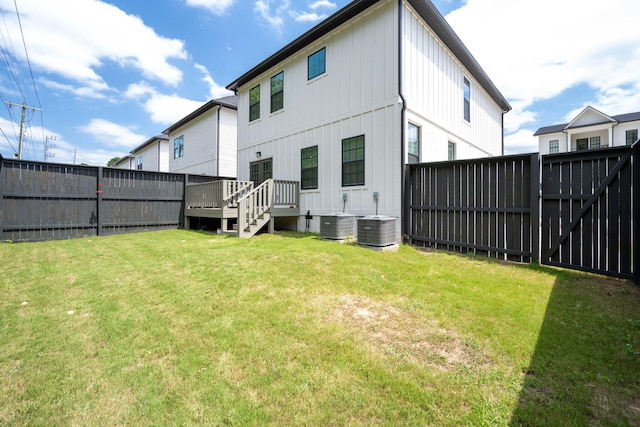 back of property with a deck, cooling unit, and a lawn