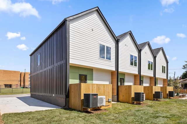 view of side of property with a yard, a patio, and central AC unit