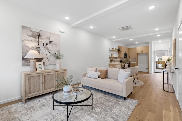 living room with beamed ceiling, light wood-type flooring, and sink