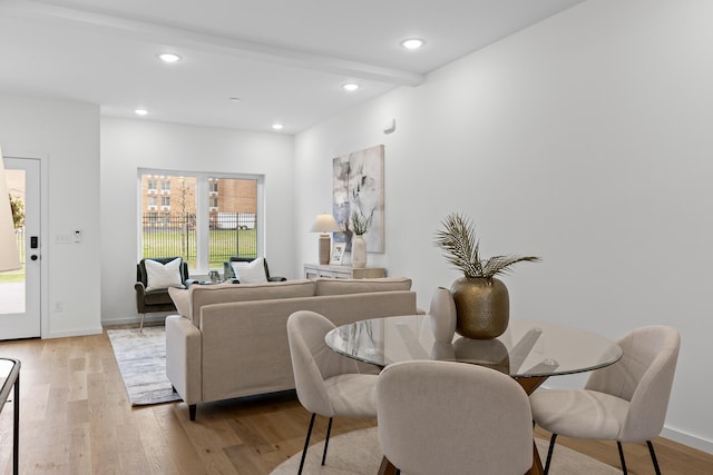 dining room featuring beam ceiling and light hardwood / wood-style flooring