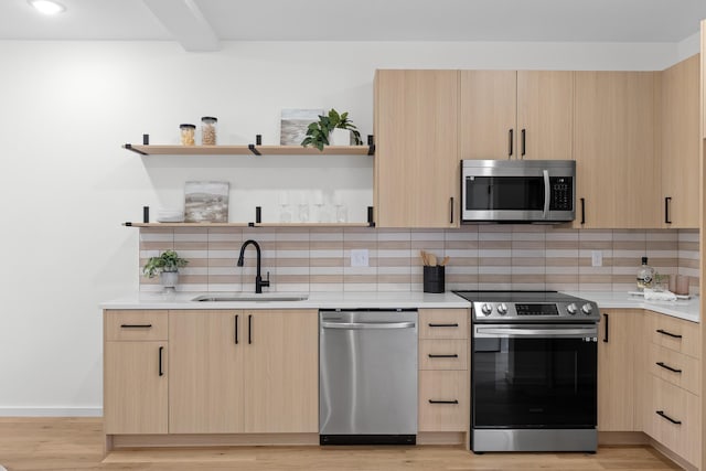 kitchen featuring light brown cabinets, sink, appliances with stainless steel finishes, tasteful backsplash, and light hardwood / wood-style floors