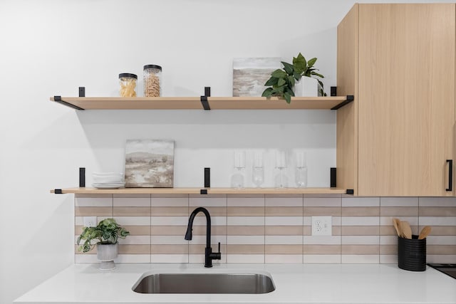 interior space with light brown cabinets, sink, and backsplash