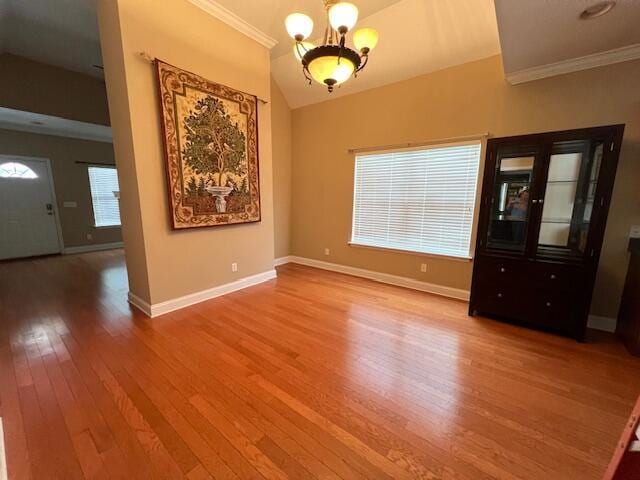 interior space with hardwood / wood-style floors, lofted ceiling, crown molding, and a notable chandelier