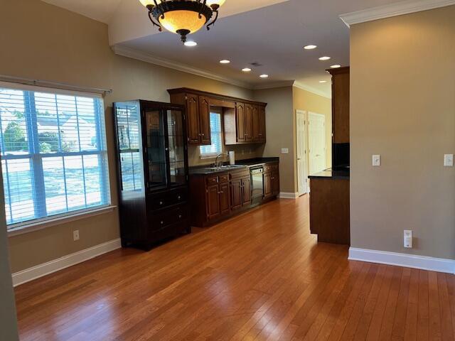 kitchen with crown molding, dishwasher, dark brown cabinets, and hardwood / wood-style flooring