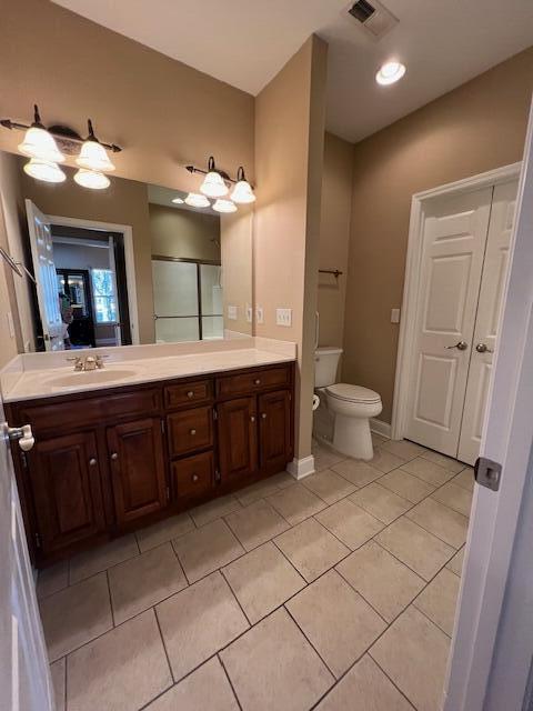 bathroom with tile patterned flooring, vanity, a shower with door, and toilet