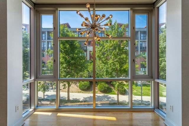 doorway to outside featuring a healthy amount of sunlight, a chandelier, and light wood-type flooring