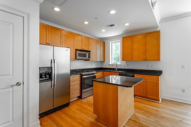 kitchen featuring a center island, sink, light wood-type flooring, ornamental molding, and appliances with stainless steel finishes